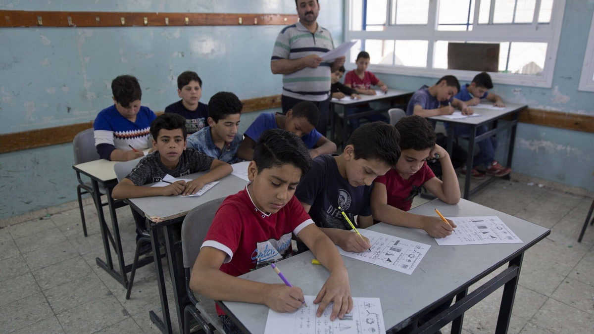 Ilustrativo: En esta foto del 26 de mayo de 2019, un profesor supervisa mientras los escolares palestinos realizan un examen final durante el último día del año escolar, en la Escuela de Niños de la UNRWA en Hebrón, en la ciudad de Cisjordania. (AP Photo/Nasser Nasser)