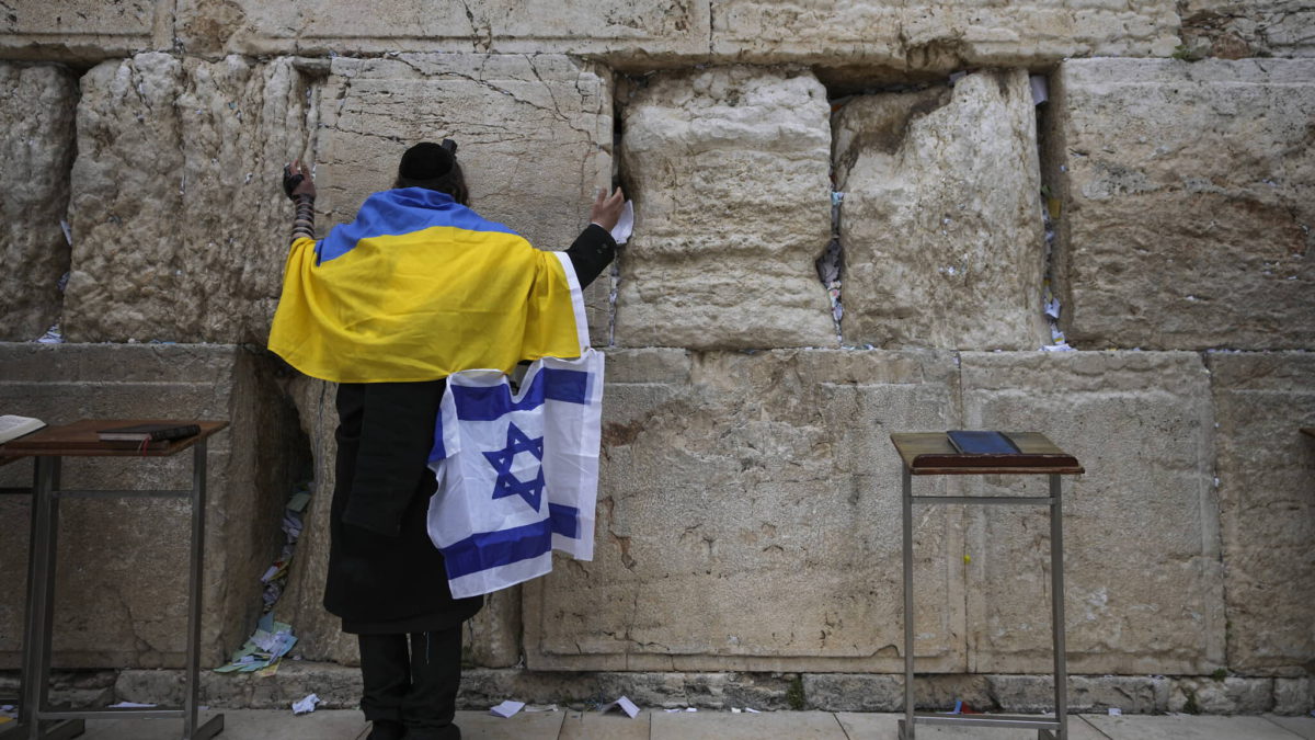 Un judío envuelto en banderas nacionales ucranianas e israelíes reza en el Muro Occidental, el lugar más sagrado donde los judíos pueden rezar en la Ciudad Vieja de Jerusalén, el 4 de marzo de 2022. (AP Photo/Mahmoud Illean)