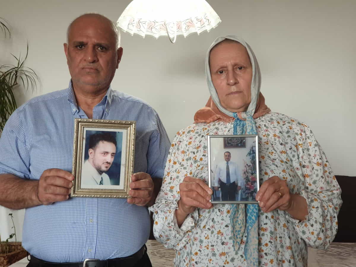 Omar Siyam, a la izquierda, y Siham Siyam, padres de Wassim Siyam, sostienen los retratos de su hijo en su casa de Alemania. (La familia de Wassim Siyam, vía AP)