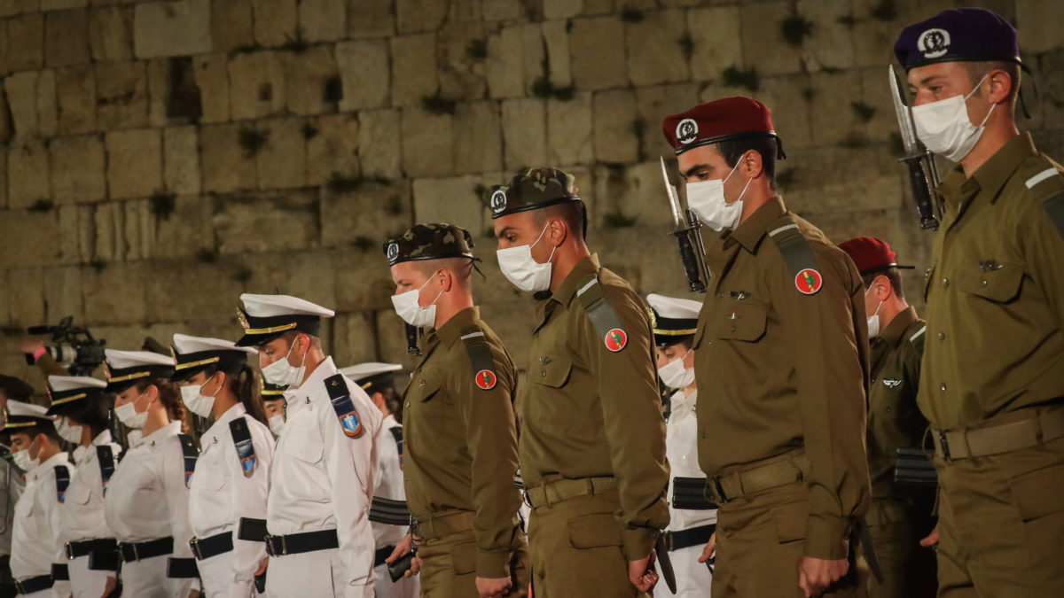Soldados israelíes permanecen inmóviles mientras suena una sirena conmemorativa durante la ceremonia que marca el Día de la Conmemoración de los soldados caídos en Israel y las víctimas del terrorismo, en el Muro Occidental en la Ciudad Vieja de Jerusalén, el 13 de abril de 2021. (Olivier Fitoussi/Flash90)