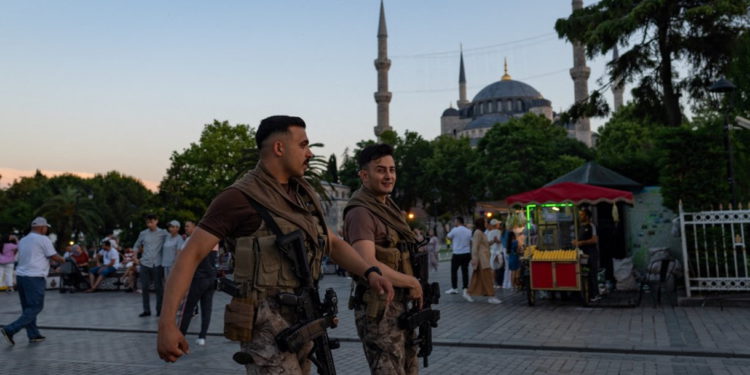Dos policías antidisturbios turcos caminan frente a la Mezquita Azul en Estambul, el 14 de junio de 2022. (Yasin Akgul/AFP)