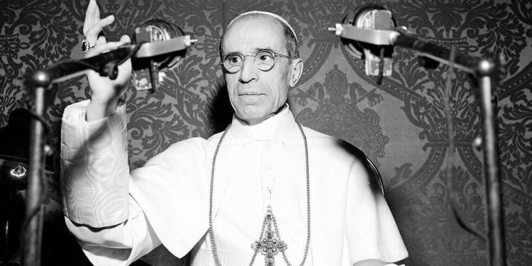 El Papa Pío XII aparece detrás de los micrófonos durante una emisión de radio desde el Vaticano en noviembre de 1947. El Papa elogió al pueblo estadounidense por sus esfuerzos para ahorrar alimentos para la Europa devastada por la guerra. (AP Photo/Luigi Felici)