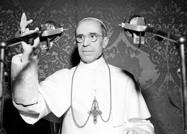 El Papa Pío XII aparece detrás de los micrófonos durante una emisión de radio desde el Vaticano en noviembre de 1947. El Papa elogió al pueblo estadounidense por sus esfuerzos para ahorrar alimentos para la Europa devastada por la guerra. (AP Photo/Luigi Felici)