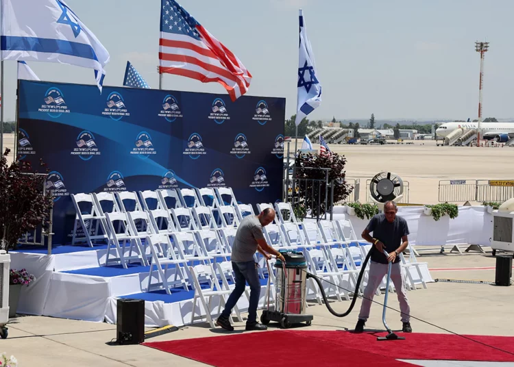 Funcionarios limpian la alfombra roja en el aeropuerto israelí Ben Gurion en Lod, cerca de Tel Aviv, el 13 de julio de 2022, antes de la llegada del presidente estadounidense Joe Biden para una visita oficial. (JACK GUEZ / AFP)