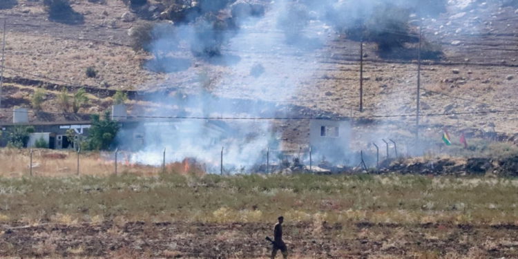Un combatiente peshmerga kurdo camina mientras el humo ondea en la zona de Zargwez, Irak, tras los ataques aéreos iraníes el 28 de septiembre de 2022. (Shwan MOHAMMED / AFP)