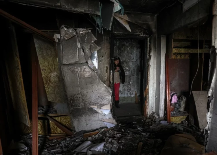 Archivo -- Maryna, de 59 años, frente a la puerta del piso dañado de sus vecinos en un edificio residencial de varios pisos tras el ataque ruso en la ciudad de Kherson, en el sur de Ucrania, el 7 de diciembre de 2022 (ANATOLII STEPANOV / AFP)
