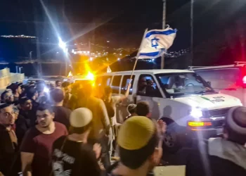 Sobreviviente de ataque pasa por Huwara con banderas israelíes
