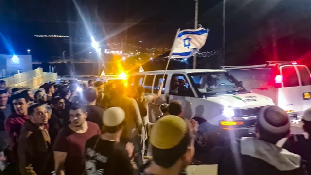 Sobreviviente de ataque pasa por Huwara con banderas israelíes