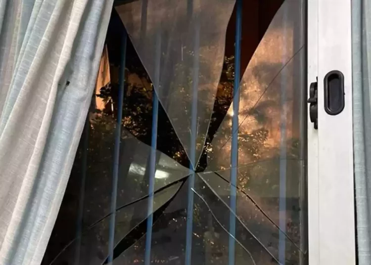 Manifestante de izquierda lanza piedra contra una ventana
