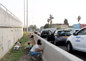 Varias personas abandonan sus vehículos para ponerse a cubierto durante un ataque palestino con cohetes desde la Franja de Gaza en una carretera principal de Tel Aviv el 24 de octubre de 2023. (Gil Cohen-Magen/AFP)