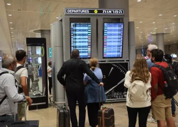 Pasajeros miran un tablero de salidas en el aeropuerto Ben Gurion, cerca de Tel Aviv, mientras los vuelos son cancelados y retrasados debido a un ataque masivo sorpresa de Hamás, el 7 de octubre de 2023. (Gil Cohen-Magen/AFP)