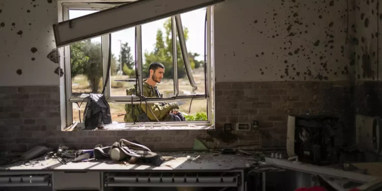 Un soldado israelí patrulla junto a una casa dañada por terroristas de Hamás en el kibutz Kissufim, en el sur de Israel, el 21 de octubre de 2023. (AP/Francisco Seco)