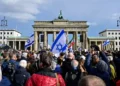 Manifestantes muestran banderas israelíes mientras asisten a una concentración en solidaridad con Israel en Berlín, 22 de octubre de 2023. (John MACDOUGALL / AFP)
