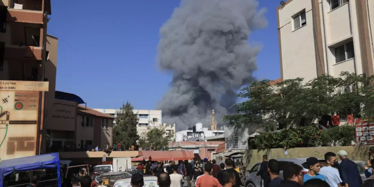 Varias personas observan el humo y el polvo tras un bombardeo israelí en Khan Younis, en el sur de la Franja de Gaza, el 26 de octubre de 2023. (Mahmud HAMS / AFP)