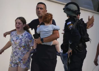 Agentes de policía israelíes evacuan a una familia de un lugar alcanzado por un cohete disparado desde la Franja de Gaza, en Ashkelon, sur de Israel, el 7 de octubre de 2023. (Foto AP/Tsafrir Abayov)
