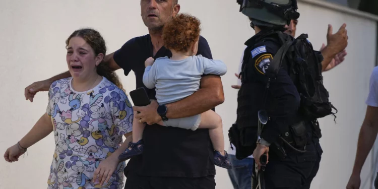 Agentes de policía israelíes evacuan a una familia de un lugar alcanzado por un cohete disparado desde la Franja de Gaza, en Ashkelon, sur de Israel, el 7 de octubre de 2023. (Foto AP/Tsafrir Abayov)