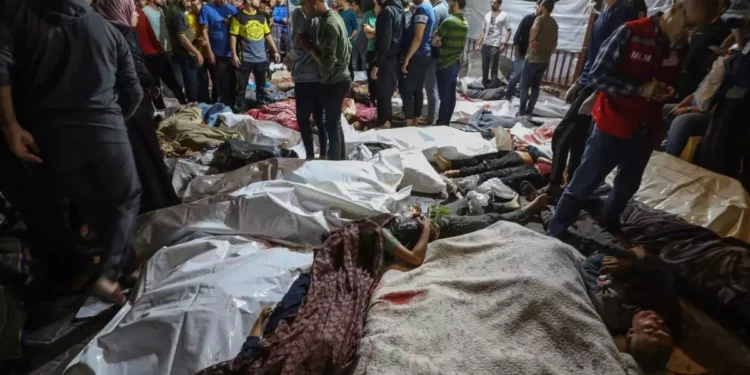 Varias personas se reúnen alrededor de los cadáveres de los palestinos muertos en una explosión en el hospital Ahli Arab (baptista), en el centro de Gaza, tras ser trasladados al hospital Al-Shifa, el 17 de octubre de 2023. (Dawood Nemer/AFP)