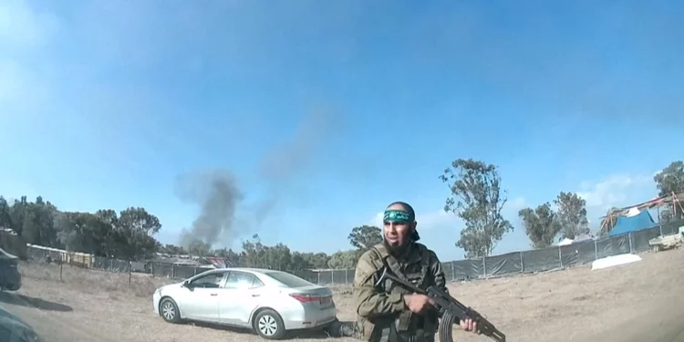 Una captura de un vídeo UGC publicado en Telegram el 9 de octubre de 2023 muestra a un terrorista palestino armado caminando por el festival de música Supernova, con un cuerpo detrás de él, cerca del Kibbutz Reim en el desierto de Negev en el sur de Israel (ANÓNIMO / AFP)
