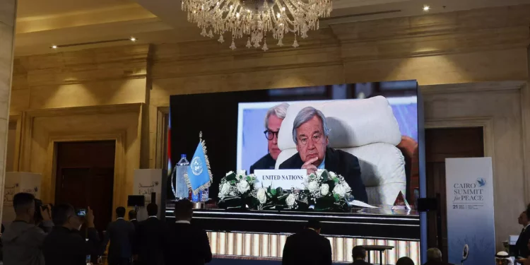 Periodistas observan una gran pantalla en la que se ve al Secretario General de las Naciones Unidas, Antonio Guterres, asistiendo a la Cumbre Internacional por la Paz organizada por el presidente egipcio en El Cairo el 21 de octubre de 2023. (Khaled Desouki/AFP)
