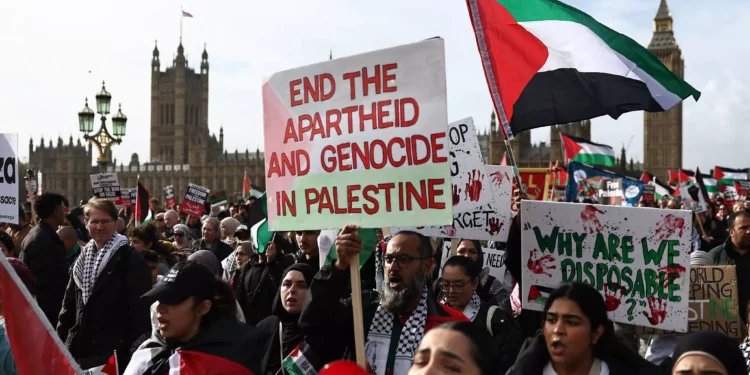 Manifestantes sostienen pancartas y ondean banderas palestinas durante una "Marcha por Palestina" en Londres el 28 de octubre de 2023, mientras piden un alto el fuego en la guerra entre Israel y Hamás. (Henry Nicholls/AFP)