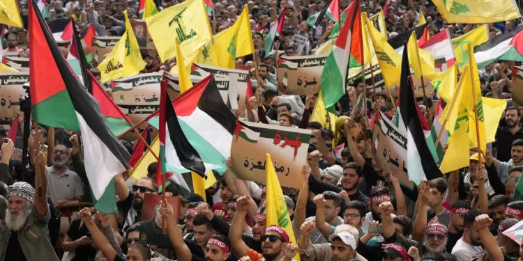 Seguidores de Hezbolá ondean banderas libanesas, palestinas y de su grupo, mientras sostienen pancartas a favor de Gaza durante una protesta para mostrar su solidaridad con los palestinos, en el suburbio sur de Beirut, Líbano, viernes 13 de octubre de 2023. (AP Photo/Hussein Malla)