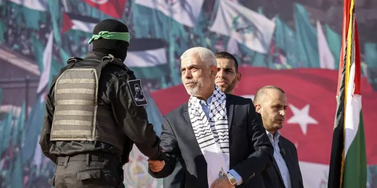 Yaha Sinwar (C), jefe de la franja de Gaza del movimiento terrorista Hamas, estrecha la mano con un luchador enmascarado del ala militar durante una manifestación que marca el 35 aniversario de la fundación del grupo palestino islamista, en la ciudad de Gaza el 14 de diciembre de 2022. (Mohammed Abed/AFP)