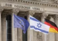 La bandera israelí ondea en medio de la europea (I) y la alemana frente al edificio del Reichstag que alberga el Bundestag, la cámara baja del Parlamento alemán en Berlín, mientras la canciller alemana pronuncia un discurso sobre el conflicto Israel-Hamás durante una sesión del Bundestag el 12 de octubre de 2023. (Odd ANDERSEN / AFP)