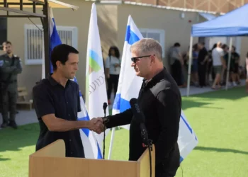 El ministro de Educación, Yoav Kisch, a la derecha, estrecha la mano de Amichai Has, director de Educación del Consejo Regional de Eshkol, en la inauguración de una nueva escuela para evacuados de la zona de Gaza, cerca del Mar Muerto, el 8 de noviembre de 2023. (cortesía de la oficina del portavoz del Ministerio de Educación)