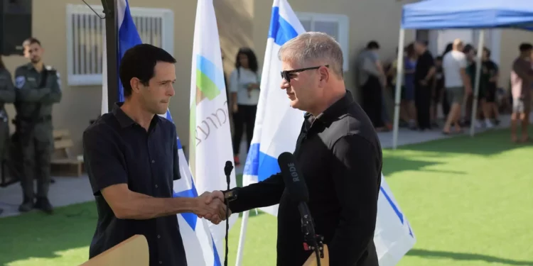 El ministro de Educación, Yoav Kisch, a la derecha, estrecha la mano de Amichai Has, director de Educación del Consejo Regional de Eshkol, en la inauguración de una nueva escuela para evacuados de la zona de Gaza, cerca del Mar Muerto, el 8 de noviembre de 2023. (cortesía de la oficina del portavoz del Ministerio de Educación)