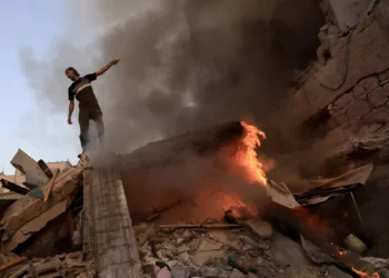 Un palestino gesticula sobre los escombros de un edificio derrumbado mientras arde un incendio tras un ataque del ejército israelí en Jan Yunis, en el sur de la Franja de Gaza, el 4 de noviembre de 2023. (Mahmud Hams/AFP)