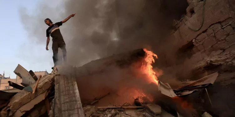 Un palestino gesticula sobre los escombros de un edificio derrumbado mientras arde un incendio tras un ataque del ejército israelí en Jan Yunis, en el sur de la Franja de Gaza, el 4 de noviembre de 2023. (Mahmud Hams/AFP)