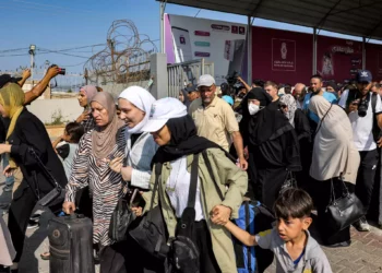 La gente camina a través de una puerta para entrar en el paso fronterizo de Rafah a Egipto en el sur de la Franja de Gaza el 1 de noviembre de 2023 (Mohammed ABED / AFP)