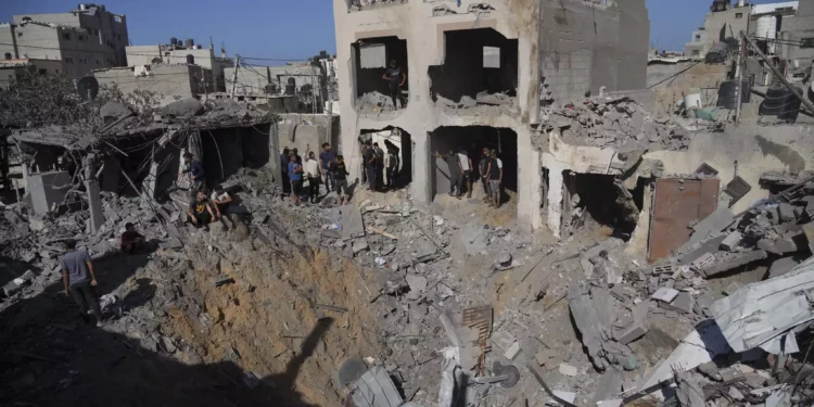 Palestinos observan edificios destruidos en un ataque israelí en Deir al Balah, Franja de Gaza, 7 de noviembre de 2023. (Hatem Moussa/AP)