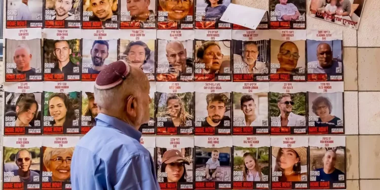 A man walks past posters of Israelis held hostage in Gaza during a protest in solidarity with the hostages' families, in Rehovot, October 29, 2023. (Meir Conforti / Protest Organizers)