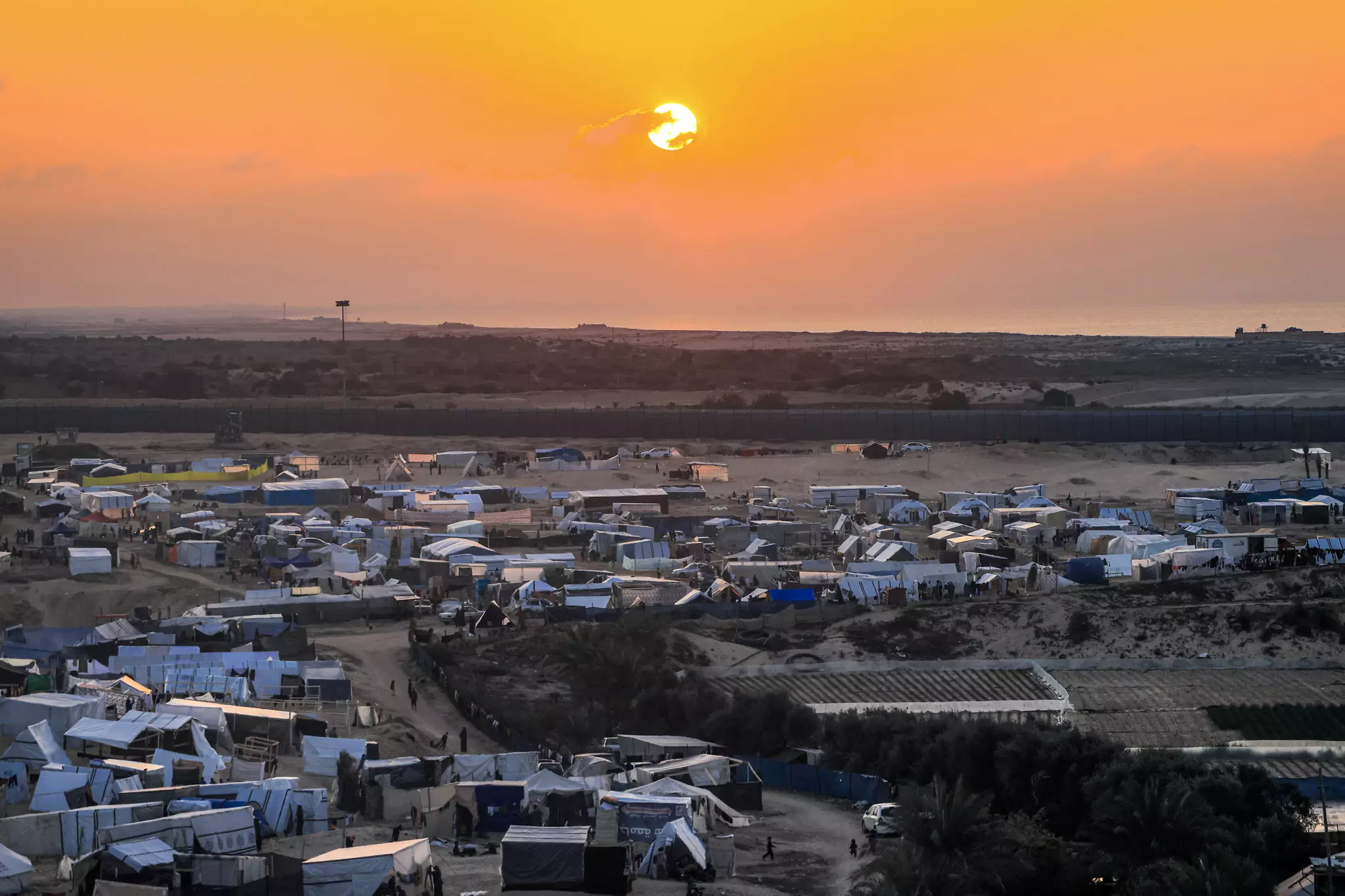 The sun sets over Egypt across the border from the tent camps of displaced Palestinians in Rafah in the southern Gaza Strip on December 31, 2023. (Photo by AFP)
