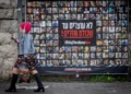 Varias personas caminan junto a fotografías de civiles retenidos como rehenes por terroristas de Hamás en Gaza, en Jerusalén, el 12 de febrero de 2024. Chaim Goldberg/Flash90)