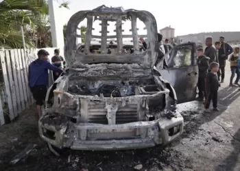 La gente se reúne alrededor del armazón de un automóvil utilizado por el grupo de ayuda estadounidense World Central Kitchen, que supuestamente fue alcanzado por un ataque israelí el día anterior en Deir al-Balah, en el centro de la Franja de Gaza, el 2 de abril de 2024. (AFP)