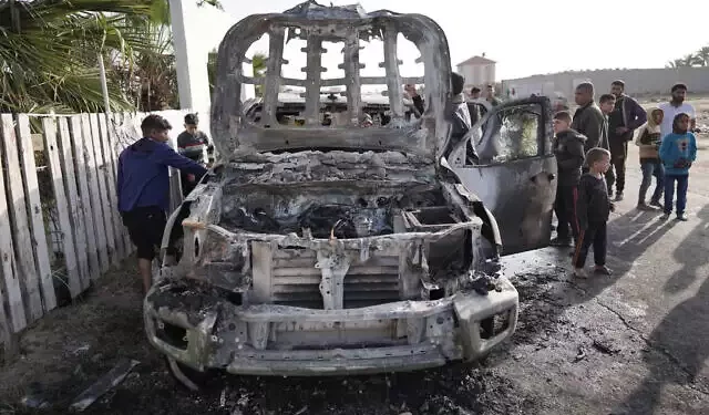 La gente se reúne alrededor del armazón de un automóvil utilizado por el grupo de ayuda estadounidense World Central Kitchen, que supuestamente fue alcanzado por un ataque israelí el día anterior en Deir al-Balah, en el centro de la Franja de Gaza, el 2 de abril de 2024. (AFP)