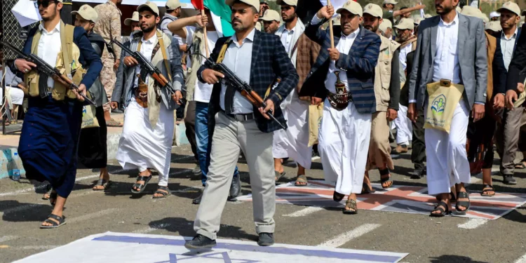 Funcionarios yemeníes armados pisan una bandera israelí mientras participan en un desfile después de 12 días de entrenamiento militar en Saná, la capital gobernada por los hutíes, el 9 de marzo de 2024 (MOHAMMED HUWAIS / AFP)