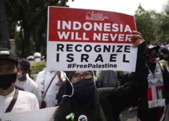 Una mujer musulmana sostiene un cartel durante una manifestación contra Israel frente a la embajada de Estados Unidos en Yakarta, Indonesia, el 21 de mayo de 2021. (Foto AP/Dita Alangkara)