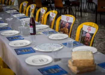 Fotos de rehenes del Kibbutz Nir Oz colocados en sillas y mesas durante un evento previo a Pesaj en el comedor del kibutz el 11 de abril de 2024. (Liron Moldovan/Flash90)