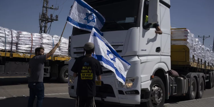 Archivo: Personas con banderas israelíes se paran frente a camiones que transportan ayuda humanitaria mientras intentan impedirles ingresar a la Franja de Gaza cerca del cruce fronterizo de Kerem Shalom, el 9 de mayo de 2024. (Foto AP/Leo Correa)