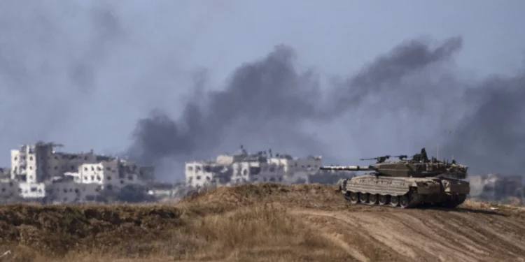 Con el telón de fondo del humo que se eleva hacia el cielo tras una explosión en la Franja de Gaza, un tanque israelí permanece cerca de la frontera entre Israel y Gaza, visto desde el sur de Israel, el lunes 13 de mayo de 2024. (AP/Leo Correa)