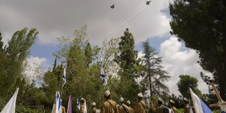 Aviones de combate israelíes sobrevuelan a los soldados que se encuentran junto a las tumbas de sus camaradas durante un ensayo en la víspera del Día de los Caídos en el cementerio militar del Monte Herzl en Jerusalén, el 12 de mayo de 2024. (AP Foto/Ohad Zwigenberg)