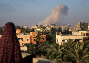 Una mujer palestina observa las nubes de humo tras un ataque israelí al sur de la ciudad de Gaza, en la ciudad de al-Zawaida, en el centro de la Franja de Gaza, el 11 de junio de 2024. (Eyad BABA/AFP)