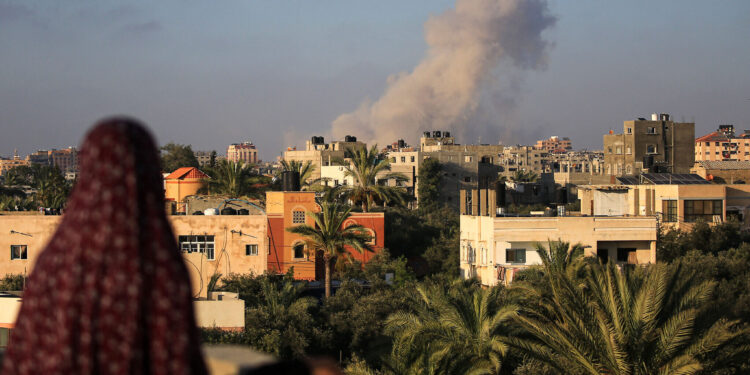 Una mujer palestina observa las nubes de humo tras un ataque israelí al sur de la ciudad de Gaza, en la ciudad de al-Zawaida, en el centro de la Franja de Gaza, el 11 de junio de 2024. (Eyad BABA/AFP)