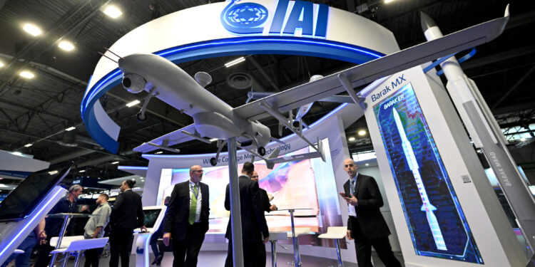 Los visitantes se encuentran en el stand de Israel Aerospace Industries (IAI) en la feria internacional de defensa y seguridad terrestre y aérea Eurosatory, en Villepinte, un suburbio al norte de París, el 13 de junio de 2022. (Emmanuel Dunand/AFP)