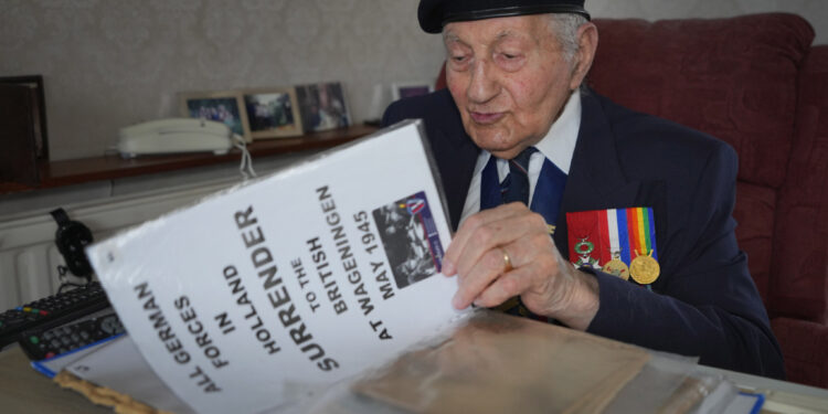 Mervyn Kersh, un veterano judío de la Segunda Guerra Mundial que participó en la Campaña de Normandía de 1944, examina documentos y periódicos de la Segunda Guerra Mundial en su casa de Londres, Gran Bretaña, el 8 de abril de 2024. (Foto AP/Kirsty Wigglesworth)