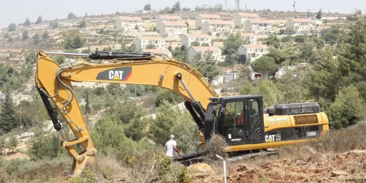 Un tractor Caterpillar limpiando terrenos para viviendas israelíes en Cisjordania, en 2012. (Oren Nahshon/Flash90)