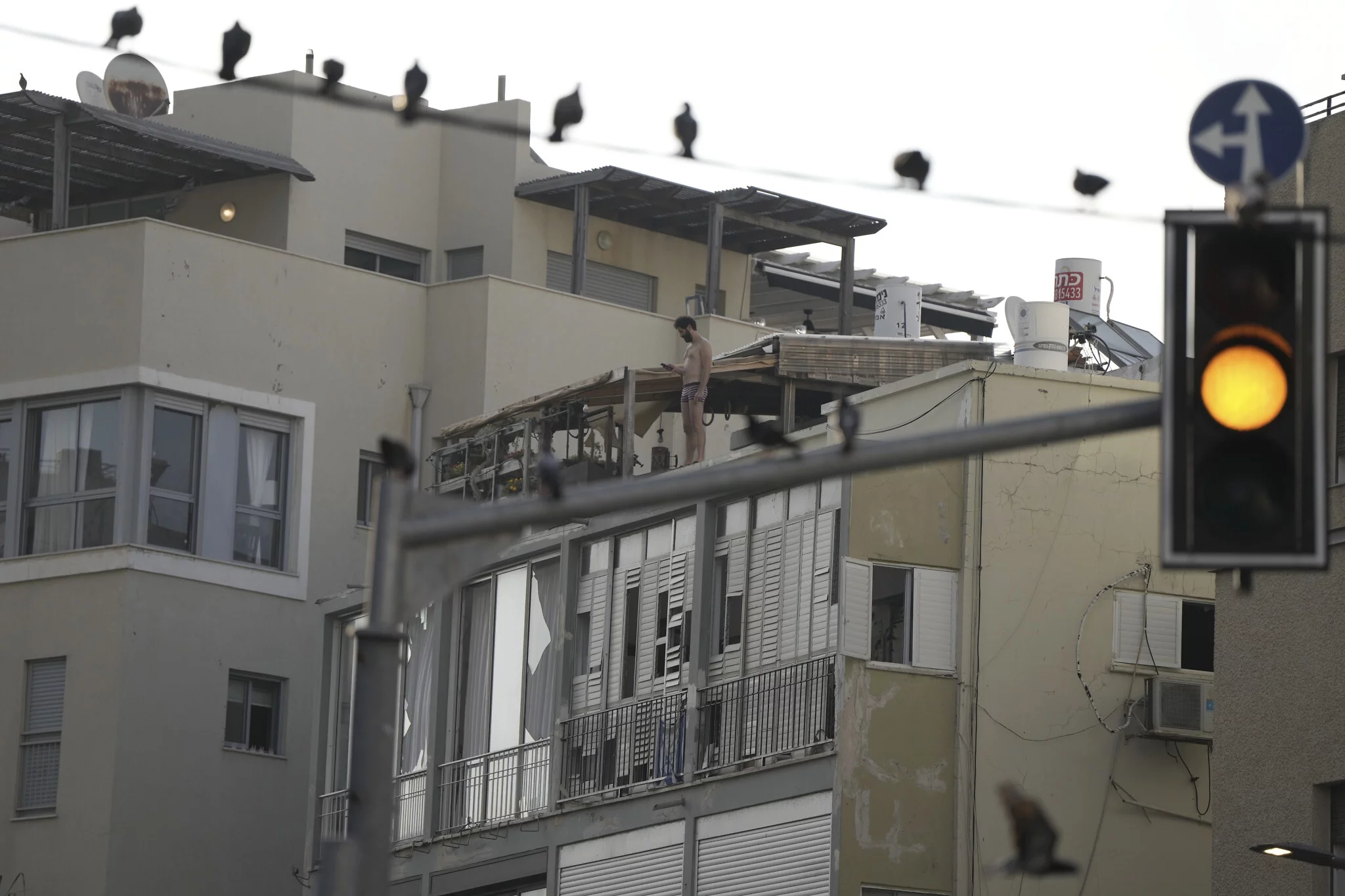 Un hombre filma la escena de un ataque mortal con drones desde la azotea de su casa en Tel Aviv, Israel, el 19 de julio de 2024. (AP/Oded Balilty)